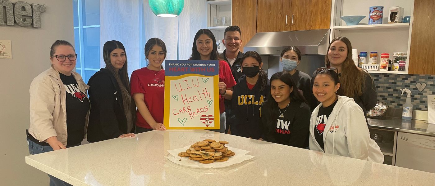 UIW students behind a counter that has cookies on it