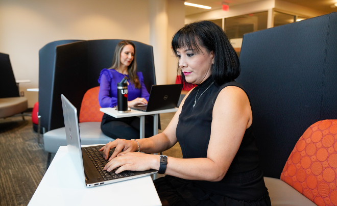 Two women in business clothes on laptops