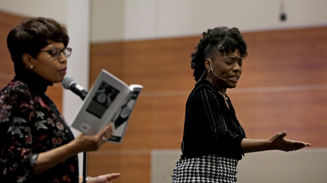 Jess Mahogany and woman reading book at microphone