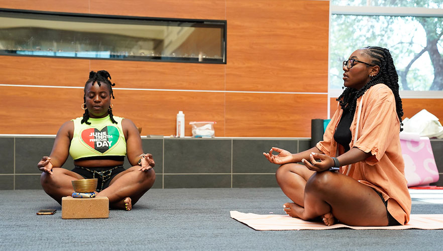 Two students performing yoga at Juneteenth event