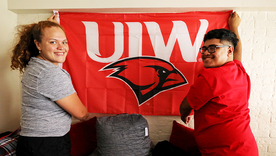 Two students hanging up flag