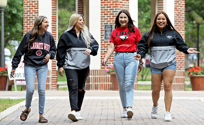 Four students walking and smiling