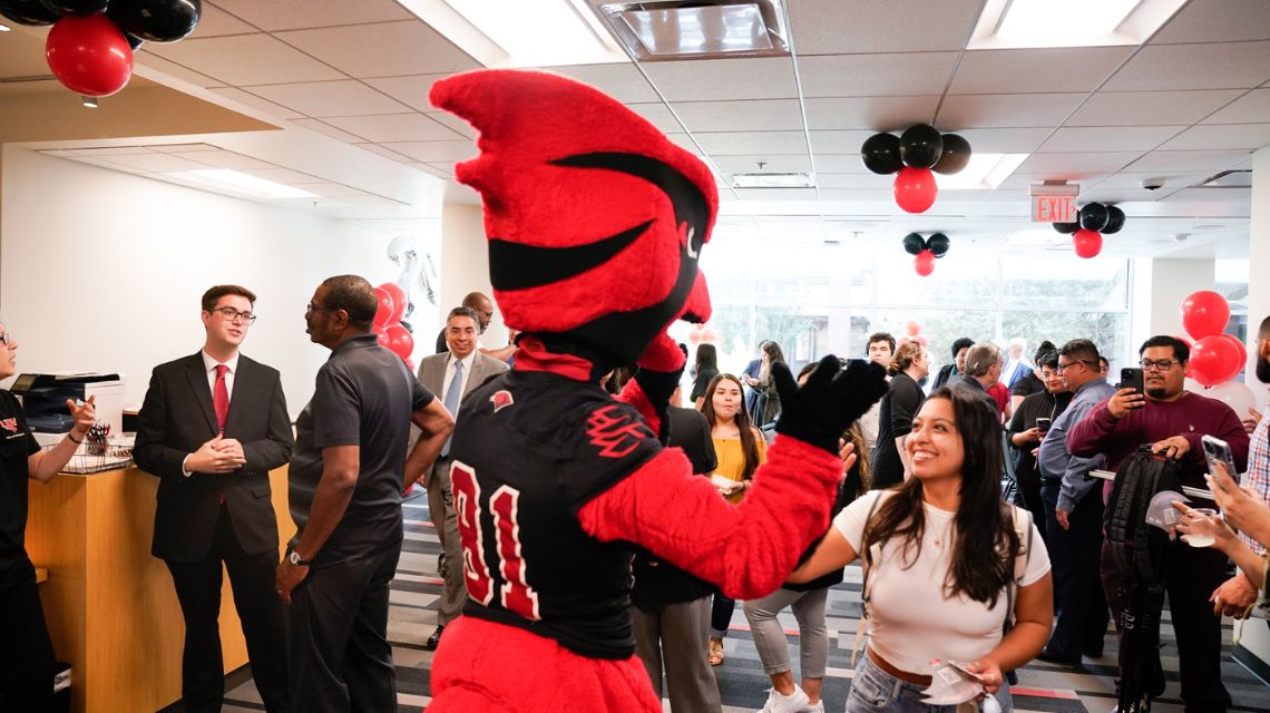 Red the Cardinal high fives a student