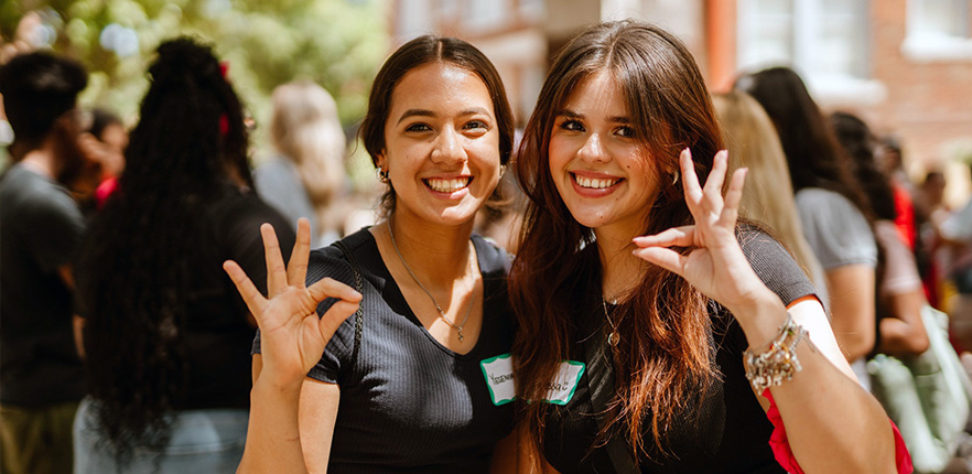 two students giving cardinal signal