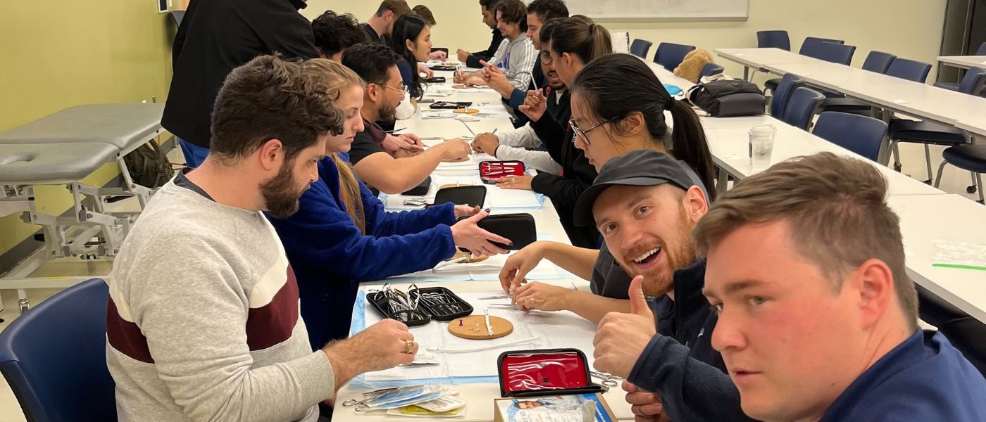 UISOM learners sit at a table practicing sutures