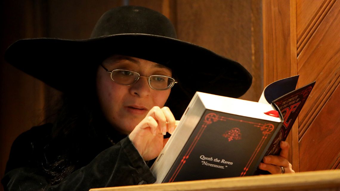 Student in black hat and glasses reading a book