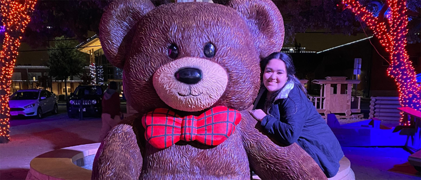 student with hugging a statue of a teddy bear