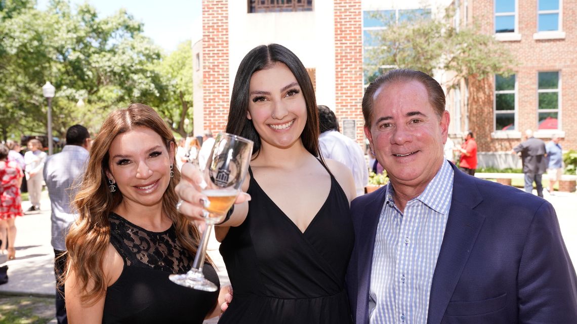 Three people with one holding a glass