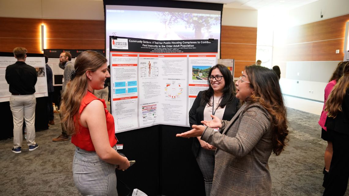 Three students talking in front of a poster