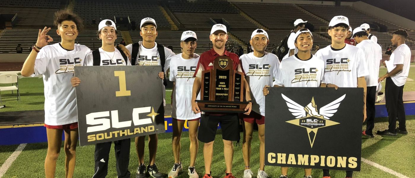 Men's track and field student-athletes with head coach holding the trophy