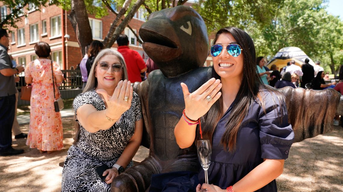 Two students with class rings next to Red