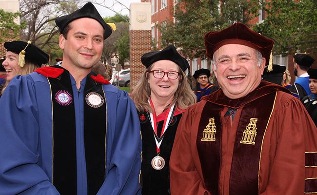 Three Faculty members in front of the University entrance