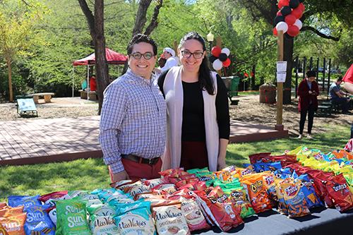 Two Staff Members behind a table of snacks