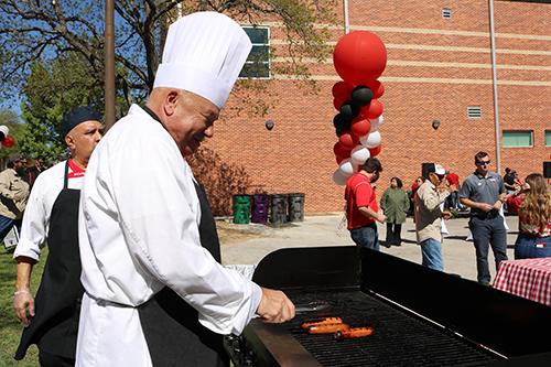 Chef cooking sausages on a grill