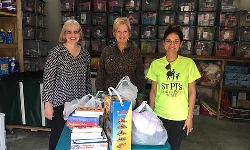 Three volunteers behind a table of donated goods