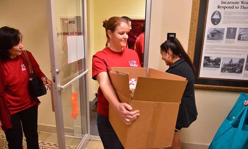A volunteer carries a box through a door