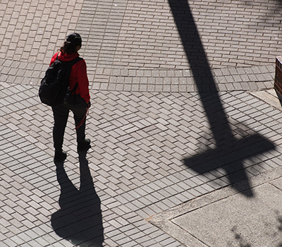 Student walking on campus with shadow of cross