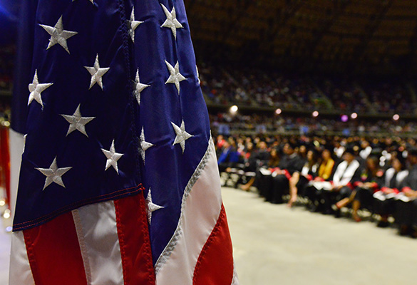 American flag with UIW graduates in the background