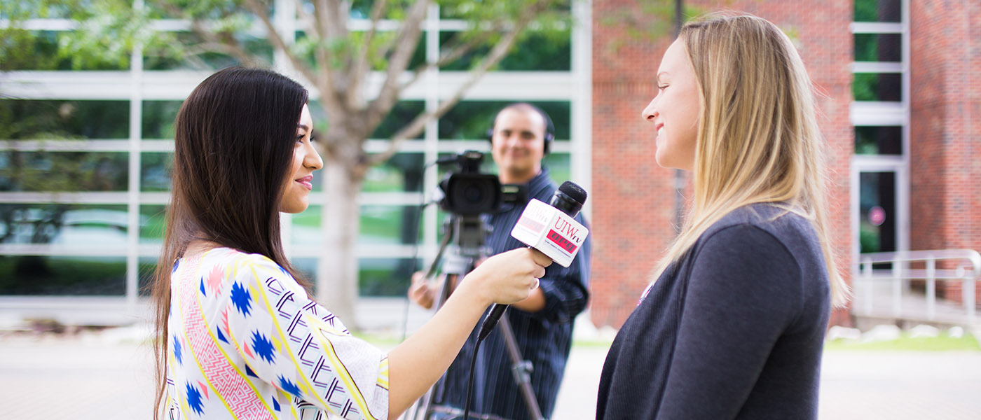 broadcasting student holding a microphone conducting an interview in front of a cameraman