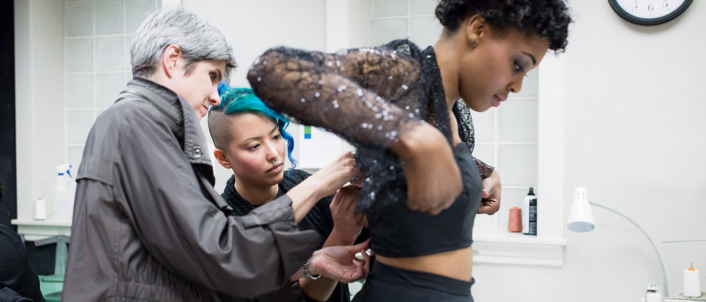 Fashion designers making adjustments to an outfit that a model is wearing