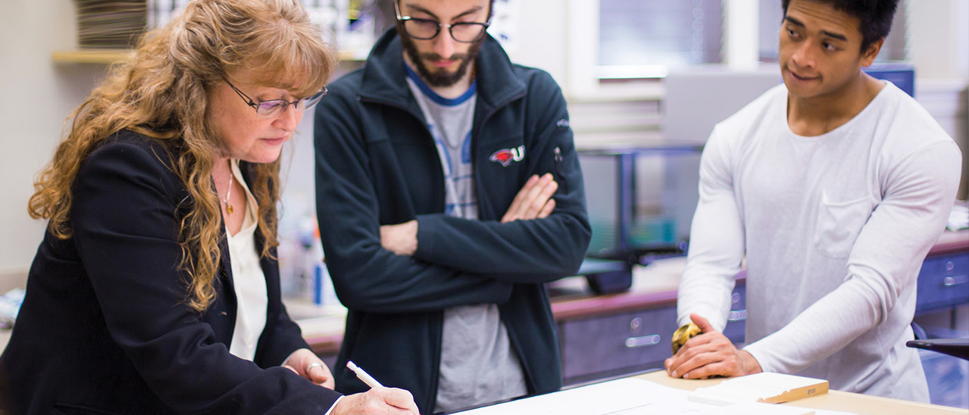 Interior design professor going over blueprints with her students