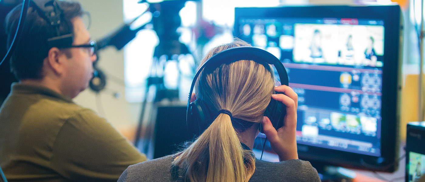 Over the shoulder view of two communication arts students in the studio working on a broadcast