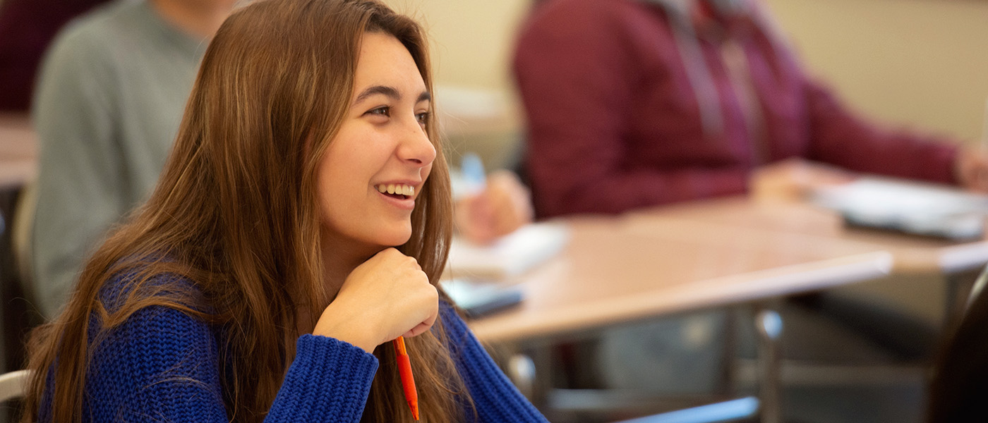 Female math student in her desk, smiling during class.