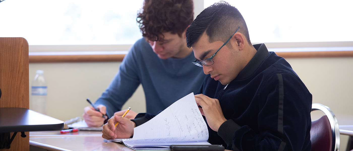 Close up of two male students taking notes during math class