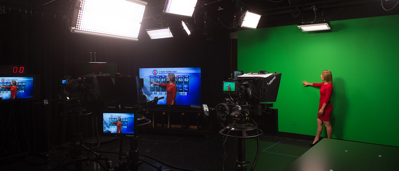 Broadcaster in red dress in studio performing a meteorology broadcast
