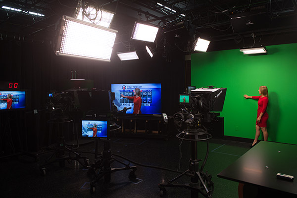 Broadcaster in red dress in studio performing a meteorology broadcast