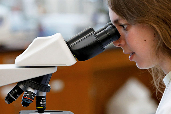 biology student looking through microscope