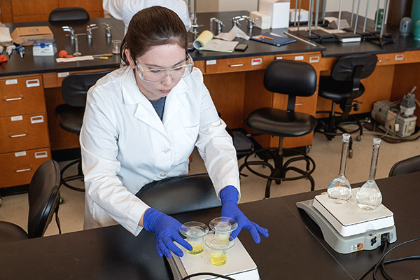 Chemistry student heating a yellow substance on a lab hot plate