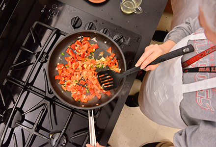 Nutrition student sauteing peppers on a pan