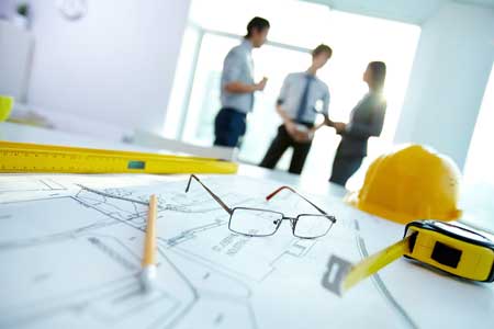 Close up of building plans with workers in the background