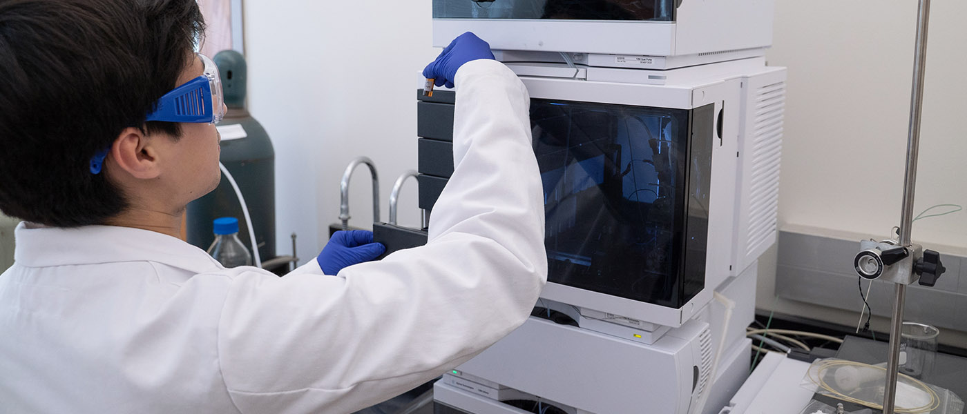 Chemistry student examining substance in a tube removed from lab equipment